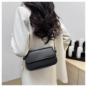 Vue arrière d'un sac bandoulière minimaliste en cuir noir porté avec une tenue de travail