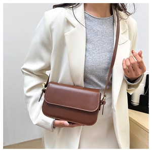 Sac sous le bras marron porté avec un blazer blanc pour un look chic et épuré