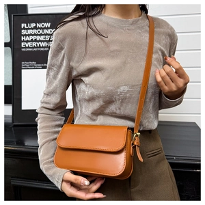 Détail du sac à main en cuir marron caramel avec boucle dorée et rabat texturé lisse