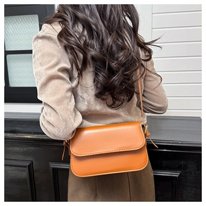 Vue arrière du mannequin portant un sac bandoulière vintage en cuir orange brûlé chic
