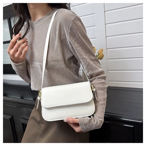 Détail du sac bandoulière blanc brillant en cuir PU avec boucle dorée sur un mannequin