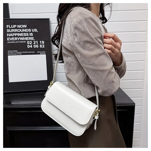 Détail d'un sac bandoulière blanc minimaliste avec boucle en métal doré et sangle