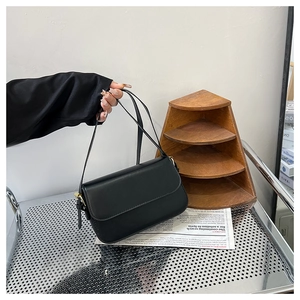 Détail d'un sac à bandoulière noir minimaliste avec rabat élégant et boucle dorée
