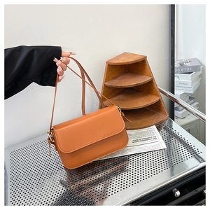 Détail d'un sac bandoulière marron caramel avec finitions dorées et cuir lisse