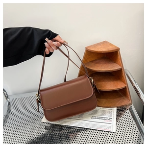 Détail du sac à main vintage en cuir marron avec bandoulière réglable et ferrures dorées
