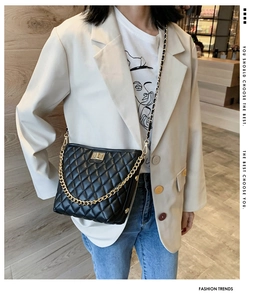 Close-up of black quilted crossbody bag with gold chain and twist-lock on model