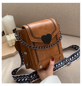 Detailansicht der braunen Vintage-Tasche mit schwarzem Herzverschluss und Kettenriemen