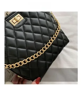 Detail shot of black quilted leather texture with gold turn-lock and chain strap