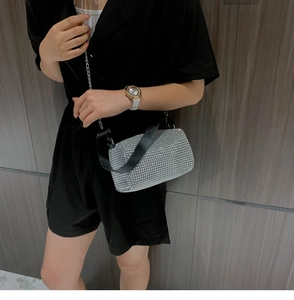 Gros plan d'un sac cylindre argenté avec strass brillants et bandoulière en cuir noir