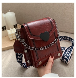 Details einer roten Vintage-Umhängetasche mit Herzschnalle und breitem Gurt