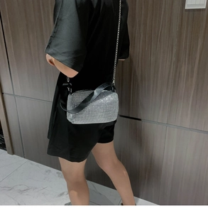 Détail d'un mini sac argenté scintillant en strass avec chaîne en métal et poignée en cuir