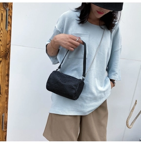 Détail du sac bandoulière noir tissé avec chaîne argentée et texture perlée