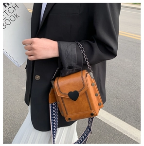Details der braunen Vintage-Tasche mit Herzschloss, breitem Gurt und Nietenverzierung