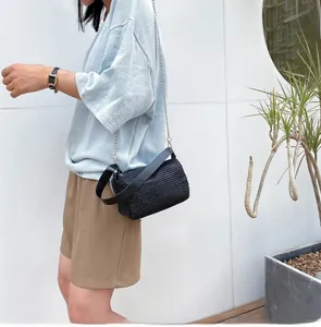 Détail du sac bandoulière tissé noir avec chaîne argentée et lanière en cuir sur modèle