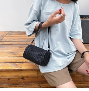 Détail du sac cylindrique en strass noirs avec poignée cuir et bandoulière chaîne