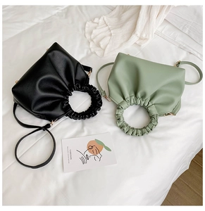 Detail of elegant matte PU leather handbags with unique pleated circular handles in black and green