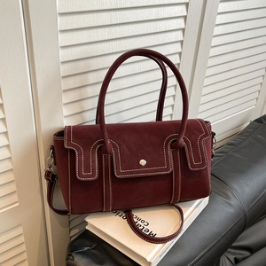 Vintage burgundy tote bag with contrast stitching and silver buckle on black leather background