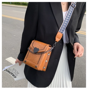 Detailansicht der braunen Vintage-Umhängetasche mit Herzschließe und Monogramm-Gurt
