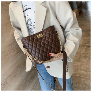 Detailed view of brown quilted crossbody bag with gold chain strap on model in beige blazer