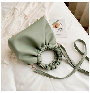 Detail of light green faux leather handbag featuring a unique cloud-like pleated round handle