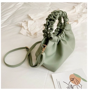 Detail of light green pleated handbag with scrunchie style handle and gold metal hardware