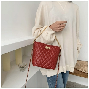 Detail of burgundy quilted crossbody bag with golden twist lock and chain strap