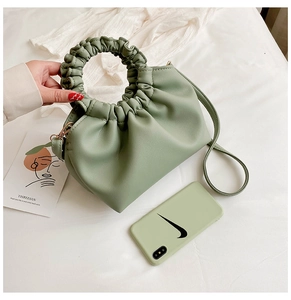 Detailed view of a sage green pleated cloud bag with scrunchie handle and shoulder strap