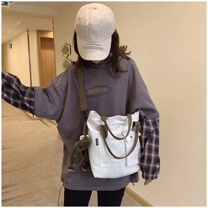 Detail of white canvas tote bag with green straps and oversized grey hoodie street style