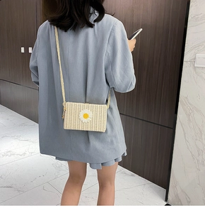 Détail d'un sac bandoulière en paille avec marguerites et bandoulière en corde