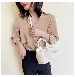 Detail of cream pleated cloud bag featuring soft leather texture and round handle
