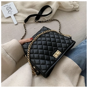Close-up of black quilted flap bag with gold chain strap and turn-lock closure