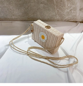 Détail d'un sac à bandoulière en paille tressée beige avec marguerite et fermoir doré