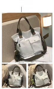 Close-up of white canvas tote bag featuring brown handles and green frog plush charm