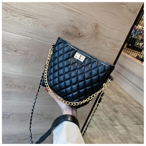 Close-up of black quilted shoulder bag with gold chain strap and metal turn-lock