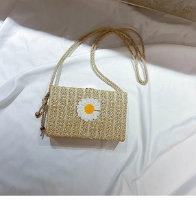 Détail d'un sac à bandoulière en paille avec broderie marguerite sur tissu crème