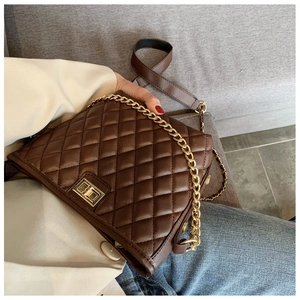 Detailed view of brown quilted crossbody bag with gold chain and twist lock on a model