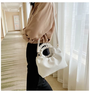 Detail of white scrunchie handle handbag with elegant cloud-like pleats and gold hardware