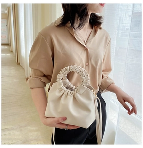 Detail of a creamy white pleated cloud handbag with a distinctive scrunchie handle design
