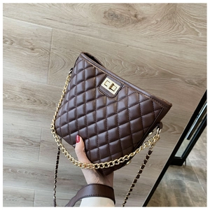 Macro view of brown quilted bucket bag featuring golden twist lock and chain strap detail