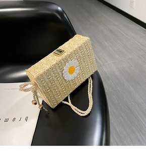 Détail du sac à main en paille tressée avec broderie marguerite et fermoir doré