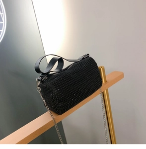 Détail d'un sac cylindrique orné de strass noirs brillants avec une bandoulière en chaîne
