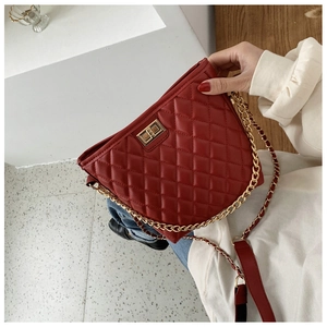 Detail of burgundy quilted leather crossbody bag with gold chain strap and turn-lock