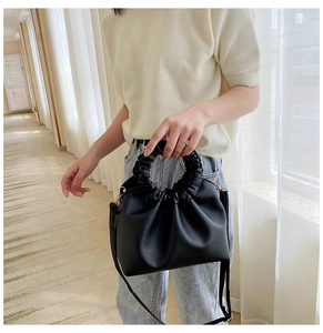 Close-up of stylish black crossbody bag with trendy pleated ruched handle detail