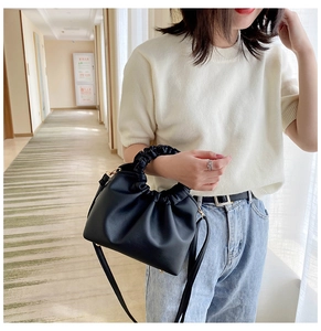 Detail of ruched handle and matte PU leather texture on a black crossbody handbag