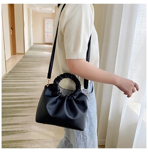 Detail of black pleated cloud handbag with golden hardware and round ruched handle