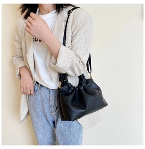 Detail of black ruched cloud bag showing soft PU leather and golden metal bottom studs