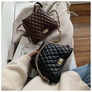 Detail of quilted leather bags with gold chain straps on beige wool coat background