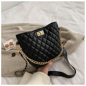 Close-up of quilted black faux leather handbag with gold chain handle and twist lock