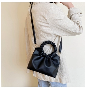 Detail of black pleated cloud bag with adjustable strap and metallic bottom studs