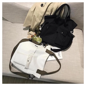 Detail of large canvas tote bags in cream and black with functional pockets and straps
